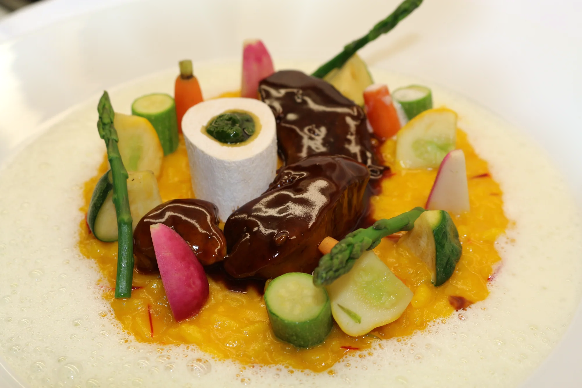Braised meat with yellow risotto, vegetables and a marrow bone