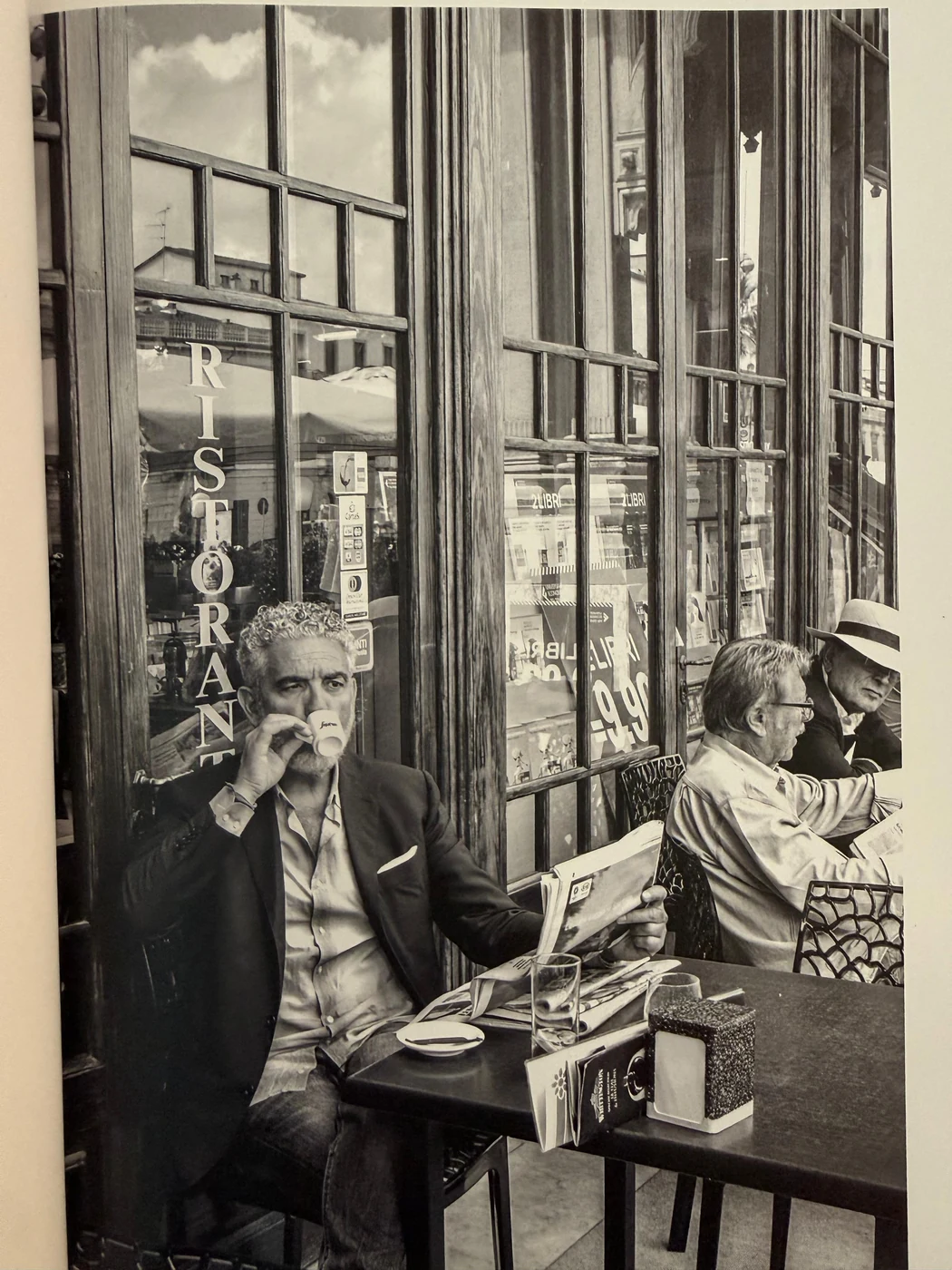 Mario Gamba with an espresso and newspaper outside a café, photographed from a printed page